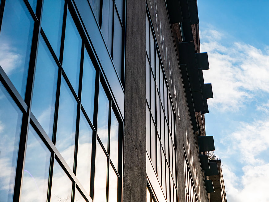 Modern Glass Building Facade Reflecting Blue Sky and Clouds