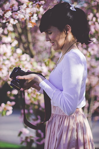 Woman with Camera Under Pink Blossoms