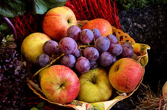 Ripe Apples And Purple Grapes In Woven Basket