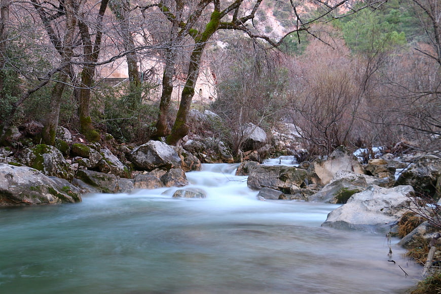 Long exposure river flowing through rocky winter forest landscape