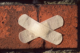 Crossed Bandages on Red Brick Wall Symbolizing Repair