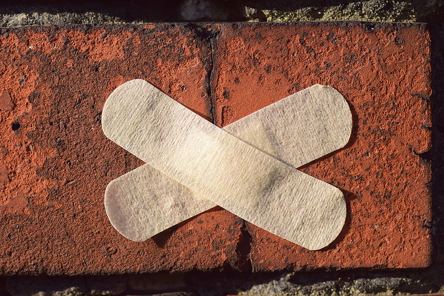 Crossed Bandages on Red Brick Wall Symbolizing Repair