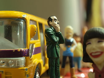 Toy Man in Green Suit Standing by Yellow Bus