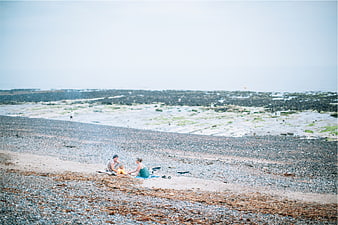 Couple having a bonfire on a pebble beach at low tide