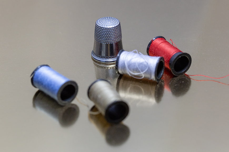 Sewing Thimble and Thread Spools on Reflective Surface