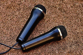 Two black microphones on textured ground