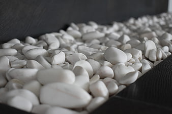 Close-up of white pebbles in a dark wooden tray