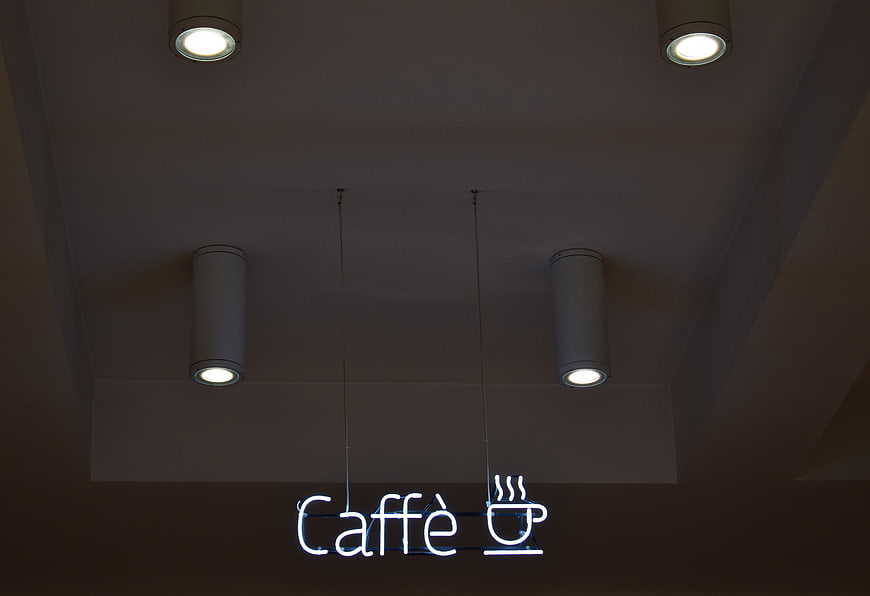 Neon Caffe Sign Hanging from Ceiling with Spotlights