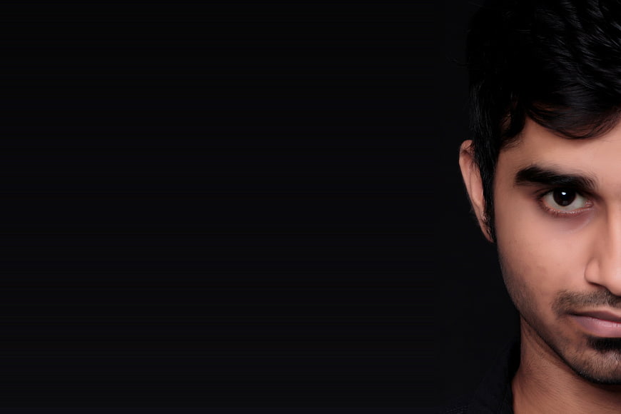 Close-up portrait of a young man with dramatic lighting on black background