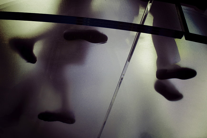 Silhouettes of feet walking on textured glass floor