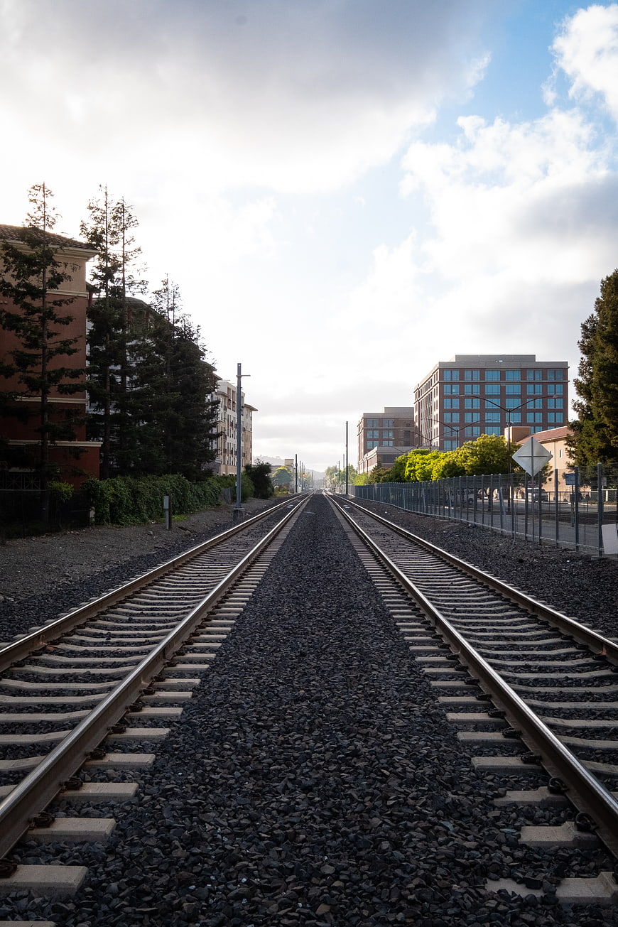 Straight Railroad Tracks Leading to Urban Cityscape