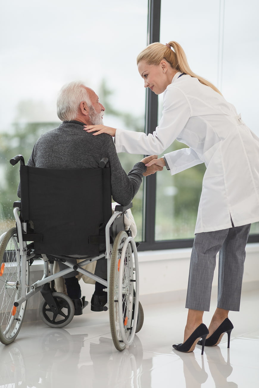 Female doctor comforting elderly man in wheelchair