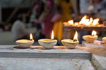 Traditional clay oil lamps burning on a wooden ledge in a temple