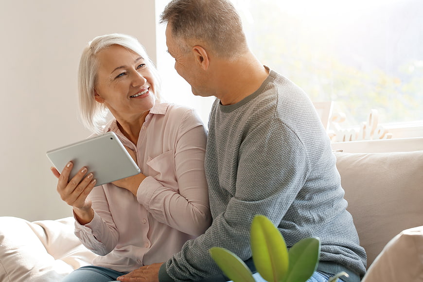 Happy Senior Couple Using Tablet on Sofa at Home