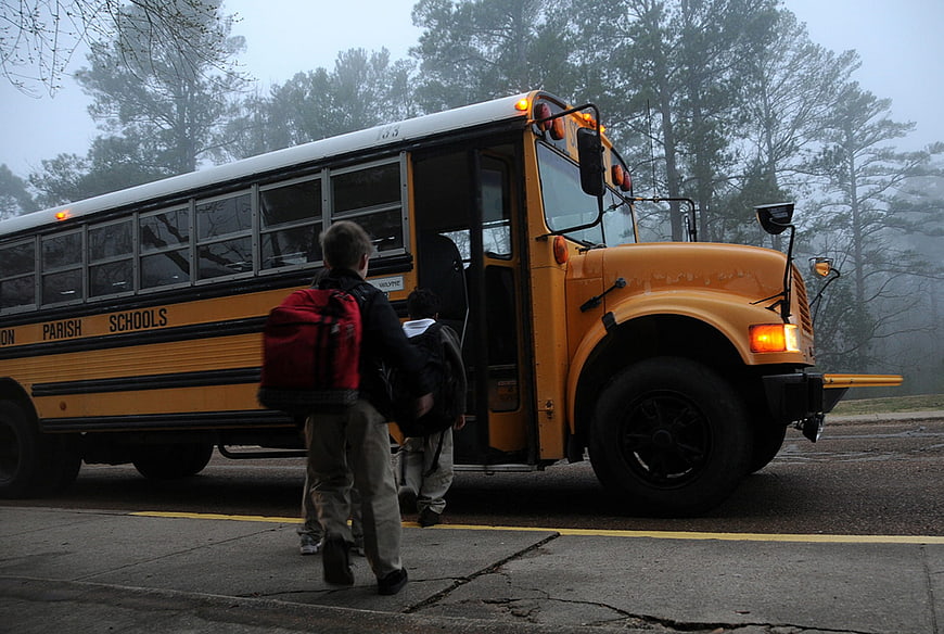 Children boarding yellow school bus on foggy morning