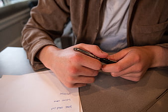 Close-up of hands holding pen over paperwork on desk