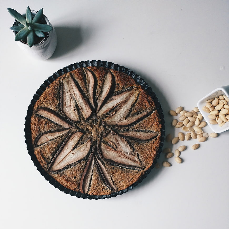 Top view of homemade pear and almond cake on white background