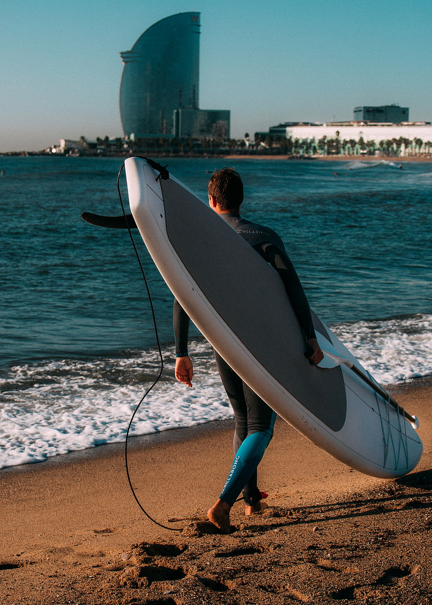 Surfer with Paddleboard Walking on Beach Toward Ocean