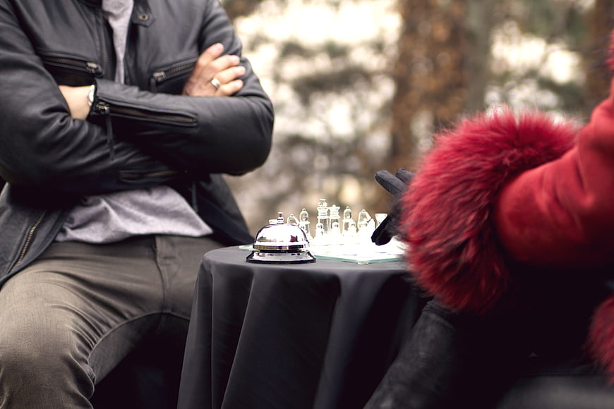 Two people playing chess outdoors in a park