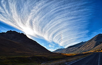 Dramatic mountain landscape with swirling clouds and winding road