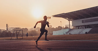 Male Athlete Sprinting On Track At Sunset