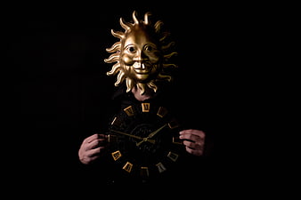 Person in golden sun mask holding clock face