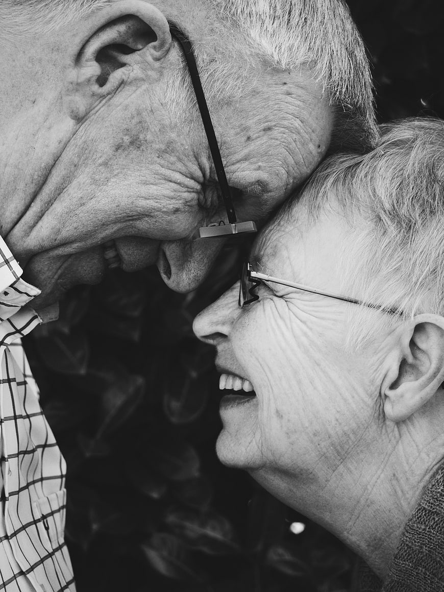 Close-up of elderly couple laughing together in black and white