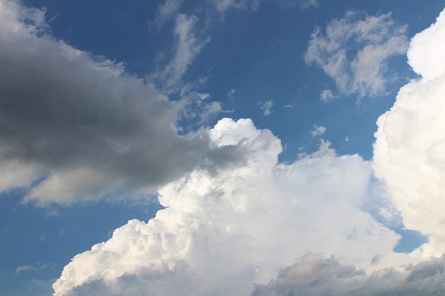 Dramatic white cumulus clouds against a deep blue sky