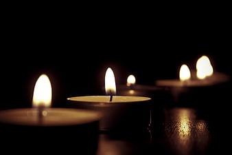 Tealight candles burning in the dark with shallow depth of field