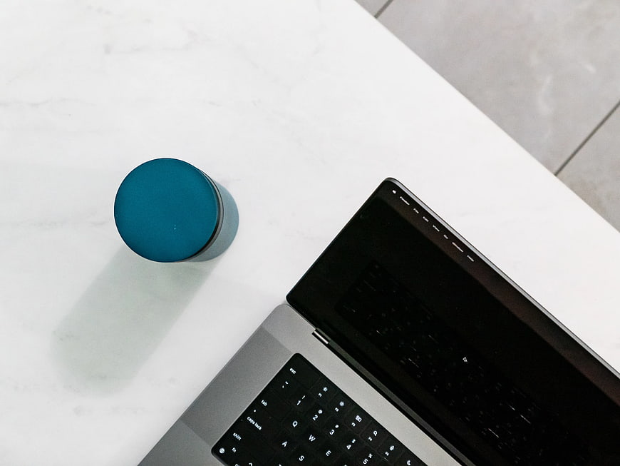 Top View of Laptop and Blue Tumbler on White Desk