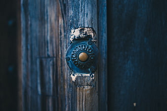Close-up of vintage brass doorbell on weathered blue wood