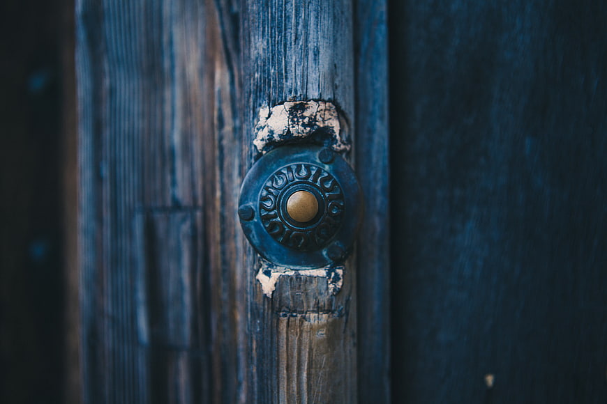 Close-up of vintage brass doorbell on weathered blue wood