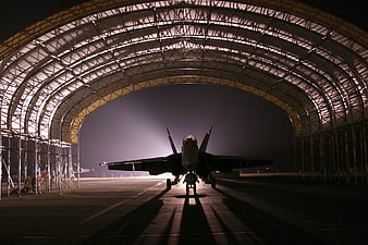 Military Fighter Jet Silhouette in Hangar at Night