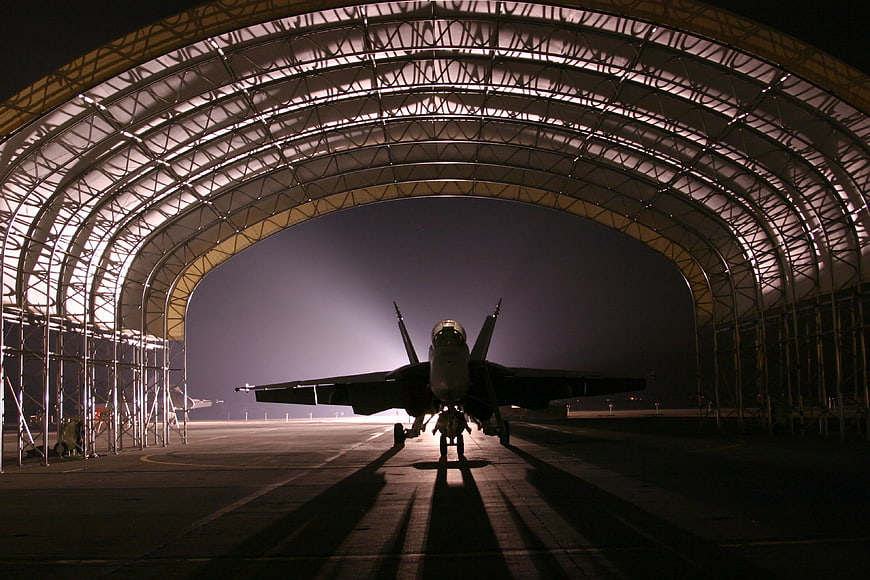 Military Fighter Jet Silhouette in Hangar at Night