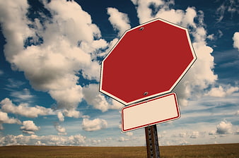 Blank Red Stop Sign Against Blue Sky with Clouds