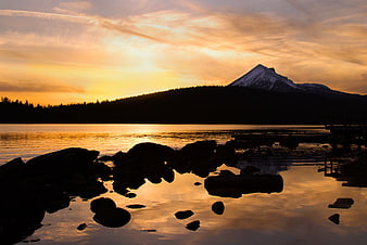 Golden Sunset Over Lake With Snow-Capped Mountain Silhouette