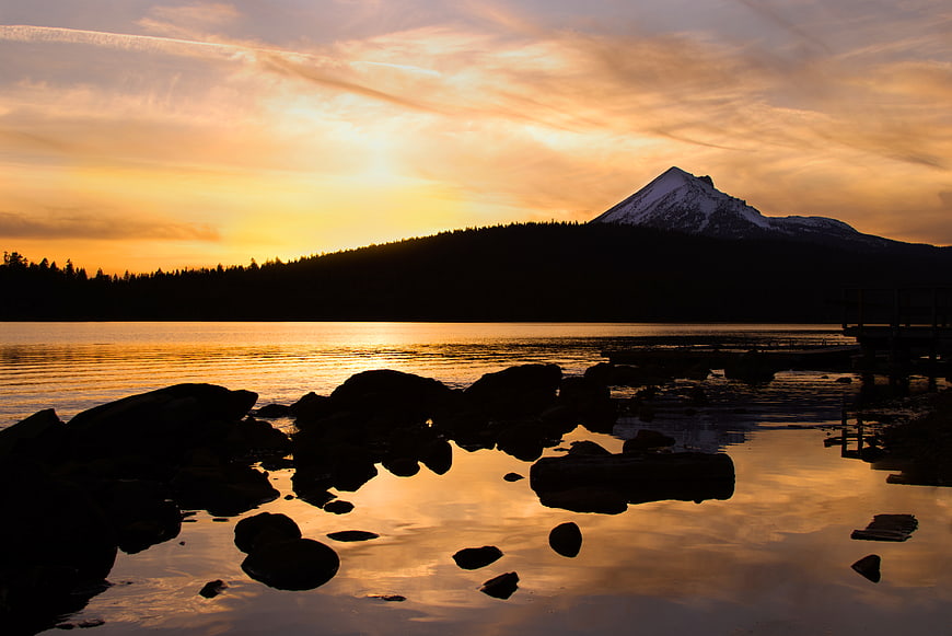 Golden Sunset Over Lake With Snow-Capped Mountain Silhouette