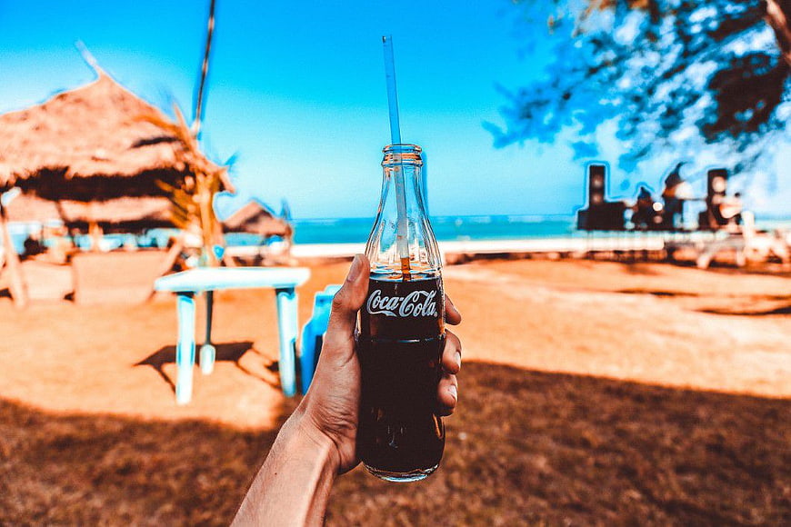 Hand Holding Coca-Cola Bottle at Tropical Beach