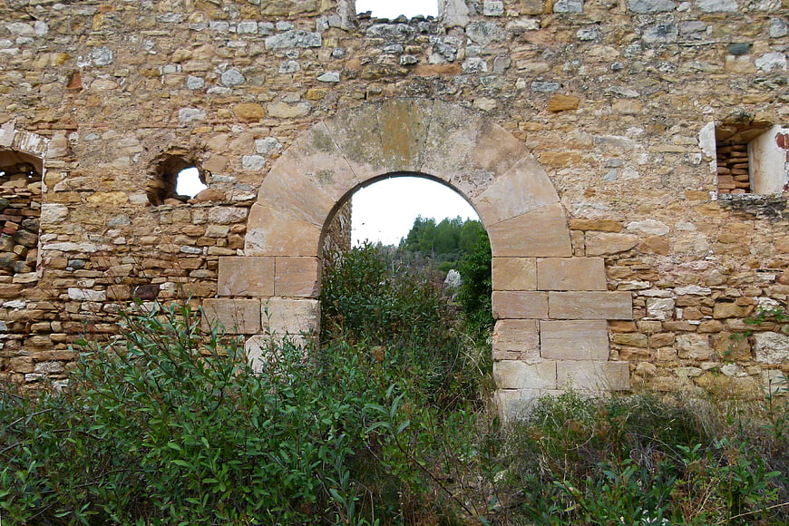 Ancient stone archway in ruined wall with overgrown vegetation