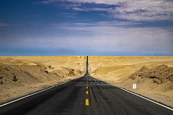 Straight Desert Highway Leading To Distant Horizon Under Blue Sky