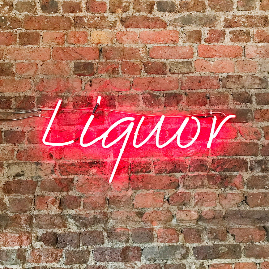 Red Neon Liquor Sign on Exposed Brick Wall