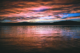 Dramatic Sunset Over Lake with Silhouetted Hills
