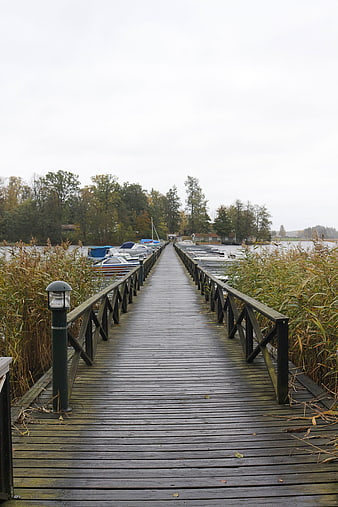 Wooden Pier Extending Over Lake with Moored Boats
