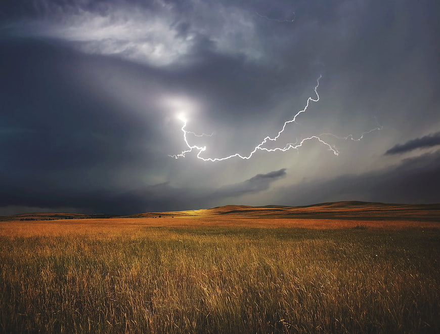 Dramatic Lightning Strike Over Golden Grassland Landscape
