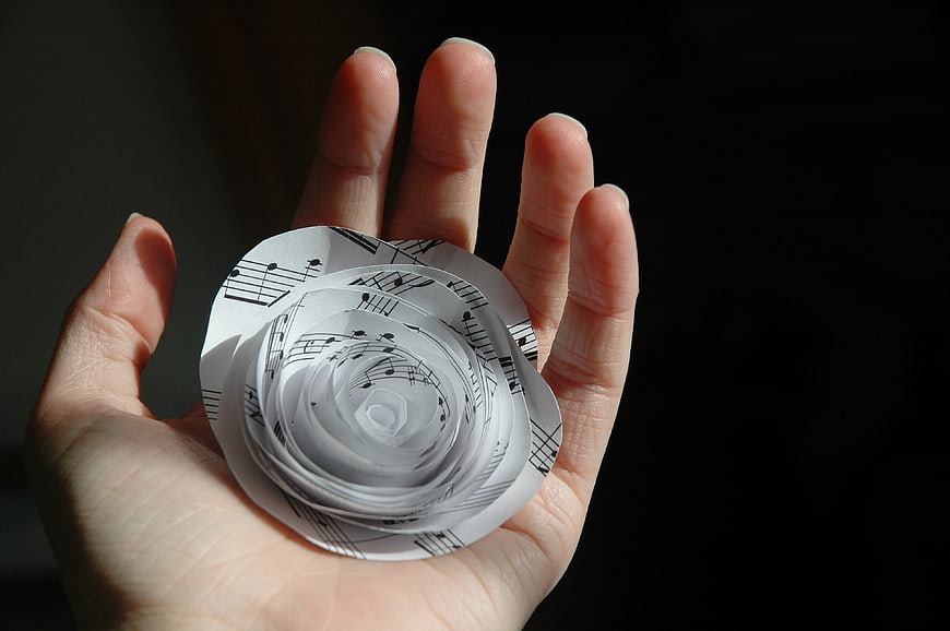 Hand holding paper rose made from sheet music