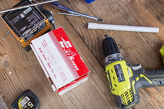 Cordless drill and screws on wooden workbench