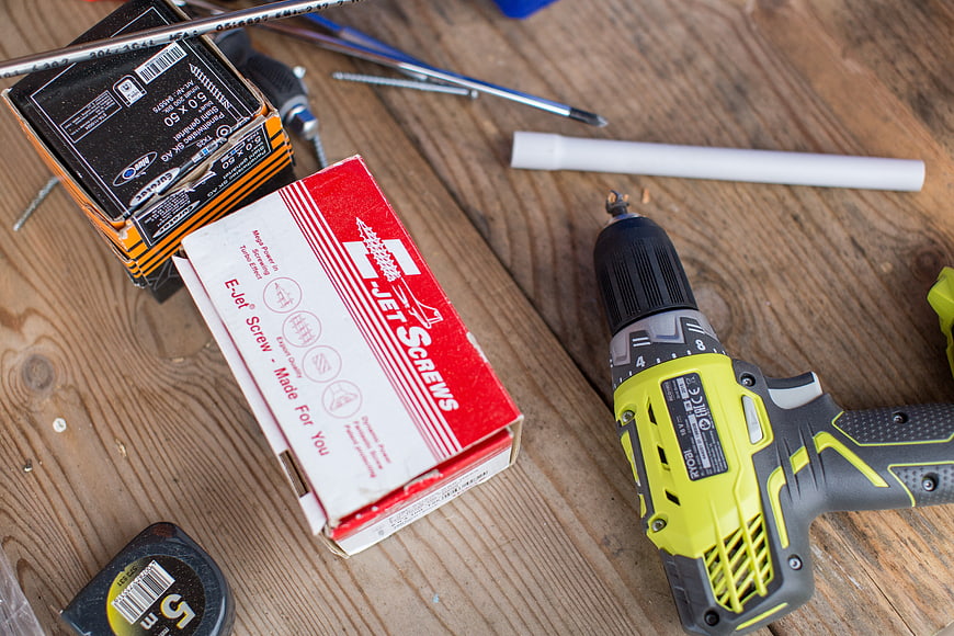 Cordless drill and screws on wooden workbench