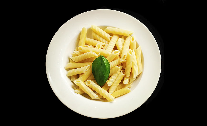 Top View of Uncooked Penne Pasta on White Plate