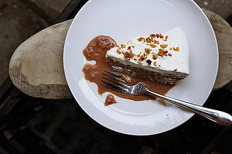 Slice of chocolate cake with caramel sauce and nuts on white plate