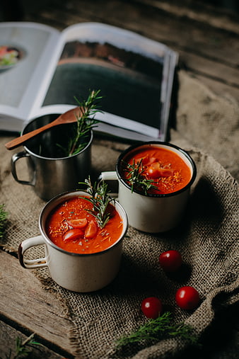 Rustic tomato soup in enamel mugs with rosemary